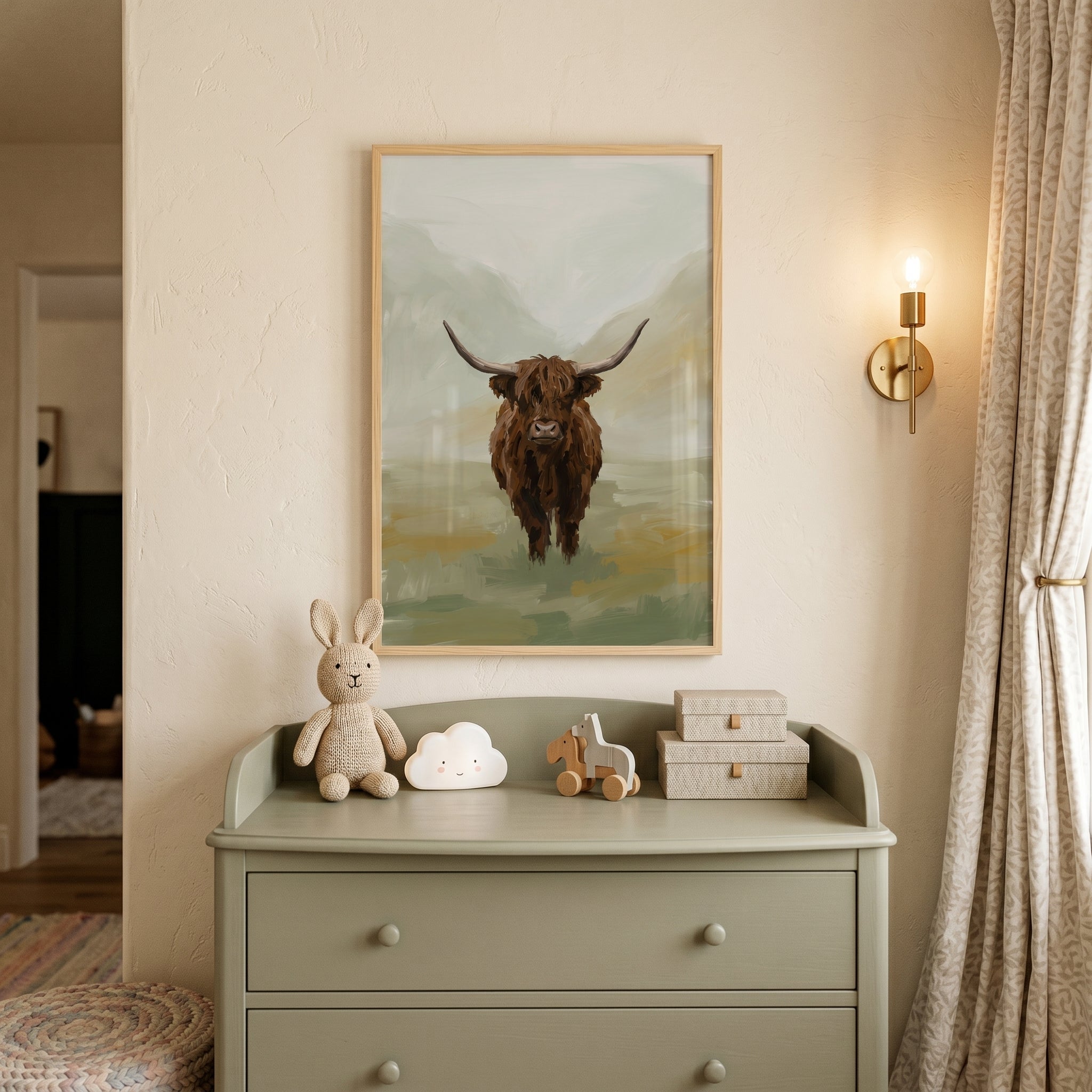Textured brown highland cow wall art above a sage dresser with a plush bunny, cloud light, and a brass wall sconce.