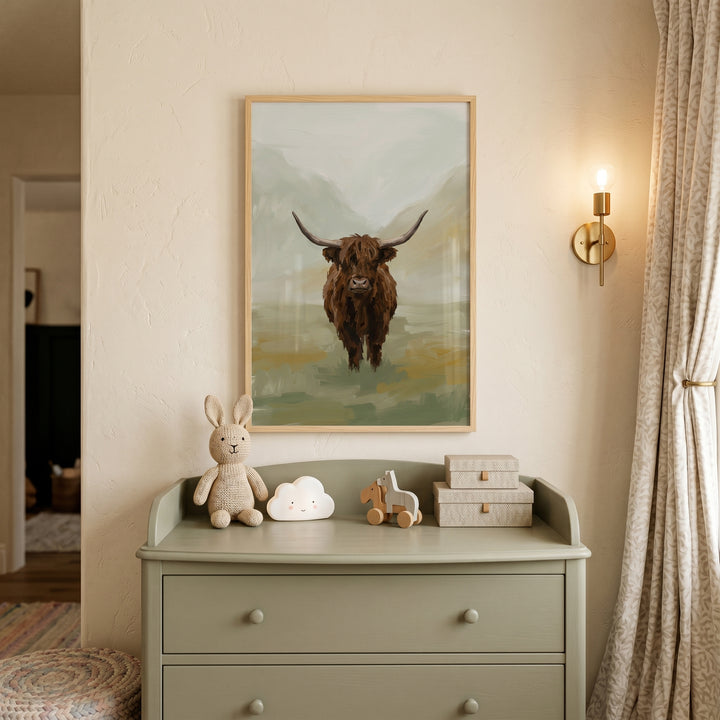 Textured brown highland cow wall art above a sage dresser with a plush bunny, cloud light, and a brass wall sconce.