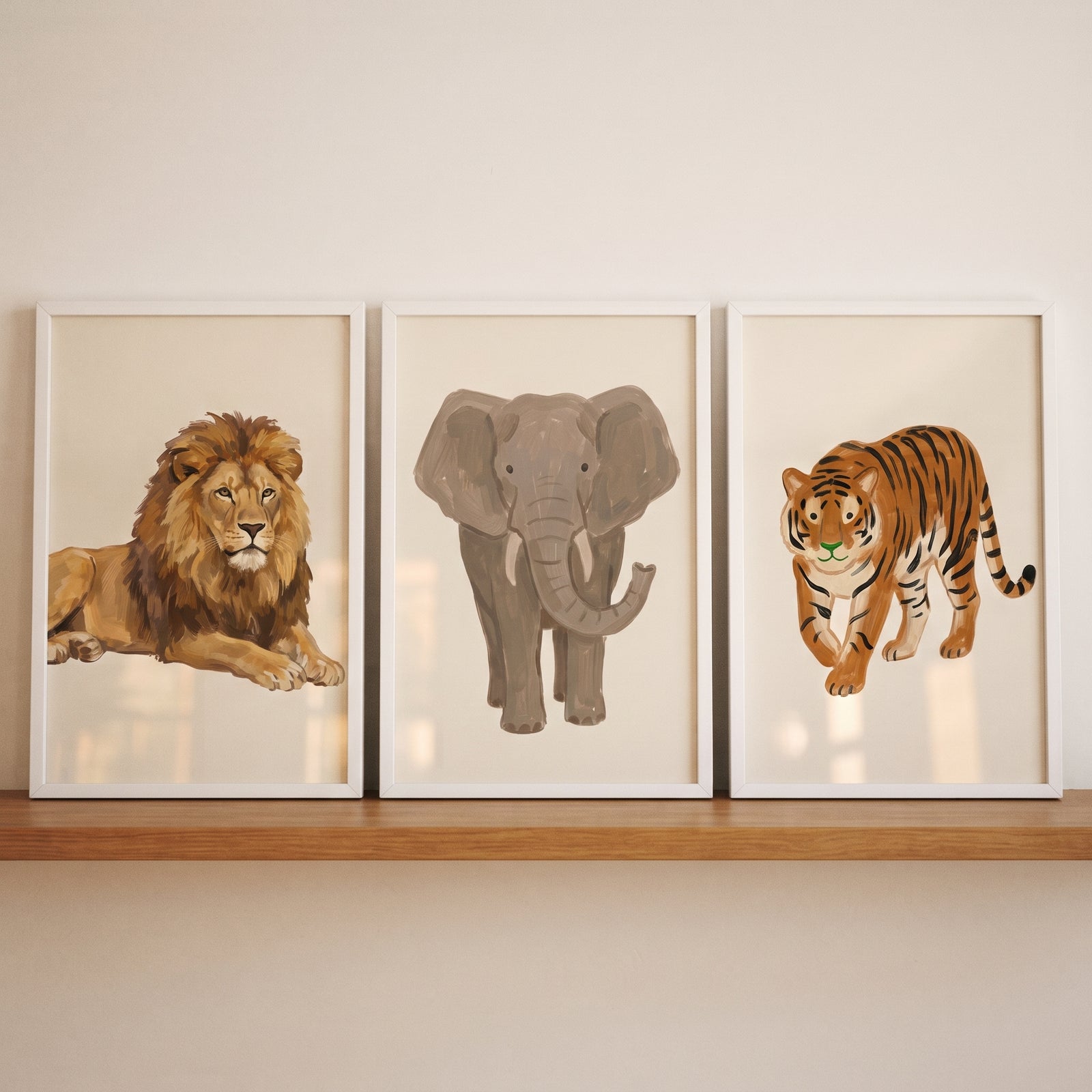 Textured brushstroke safari animals wall art set of 3 with a lion, elephant, and tiger in white frames on a wood shelf.