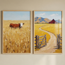 Close view of two framed countryside paintings on a cream wall. One features a single brown and white cow standing in a wheat field and the other shows a pale road curving through yellow fields toward a red barn beneath a soft blue sky.