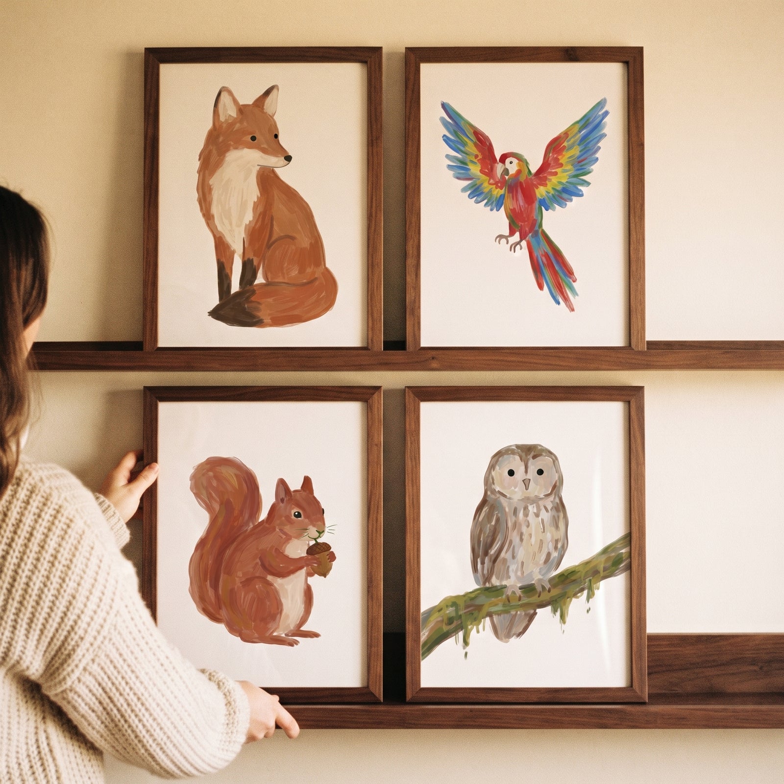 Woman arranging a textured neutral palette animals wall art set of 4 featuring a fox, parrot, squirrel, and owl.