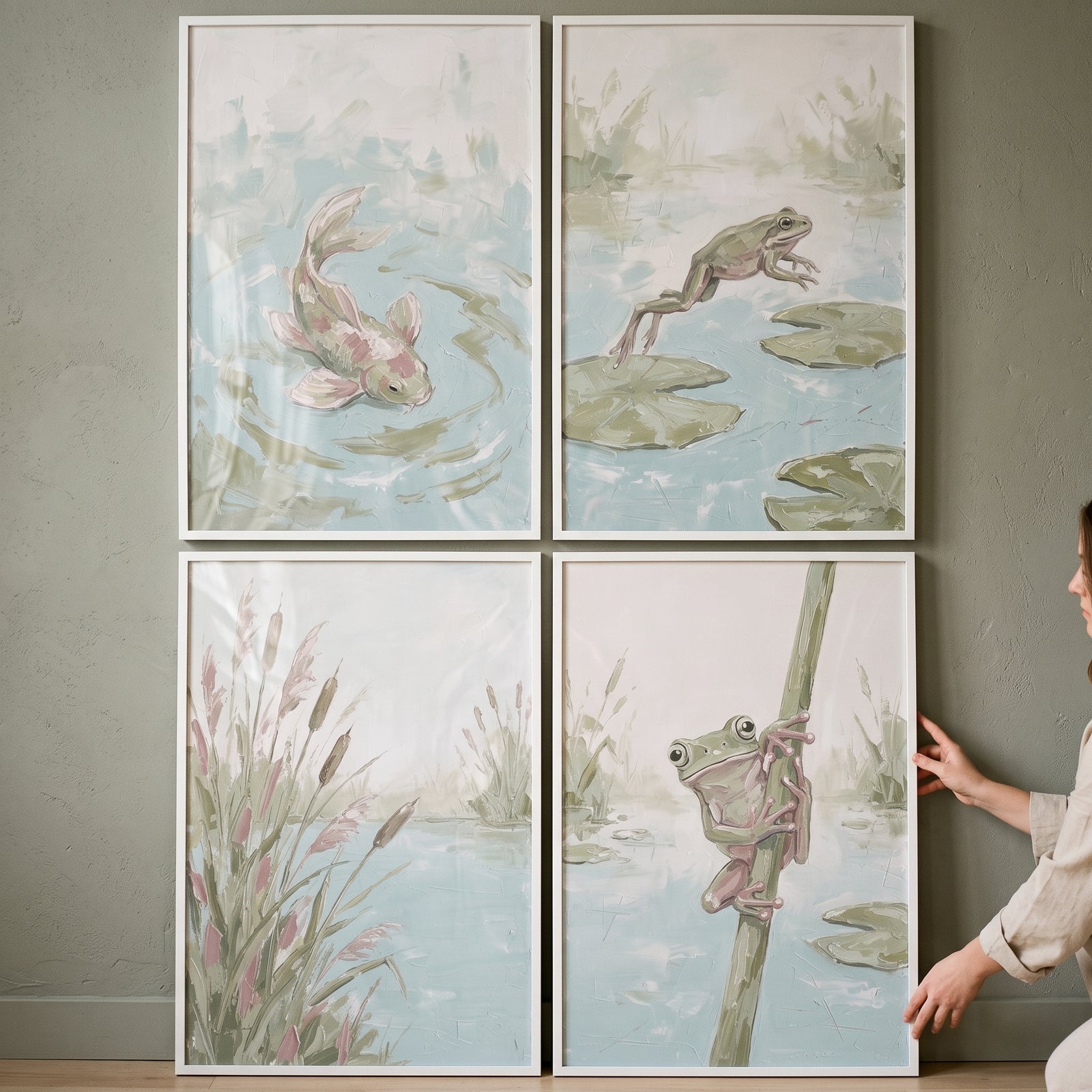 Textured sage pond wall art set of 4 featuring fish, frogs, and reeds in soft tones, being hung on a wall by a woman.