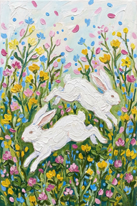 Two white rabbits leap through a lush field of colorful wildflowers in shades of yellow, pink, and blue. Petals float in the air around them, adding movement and a lively, playful energy to the scene.
