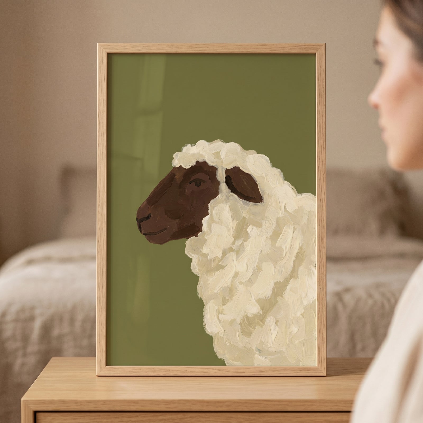 Thick texture woolly sheep wall art in a wooden frame shows a dark-faced sheep against an olive green background.