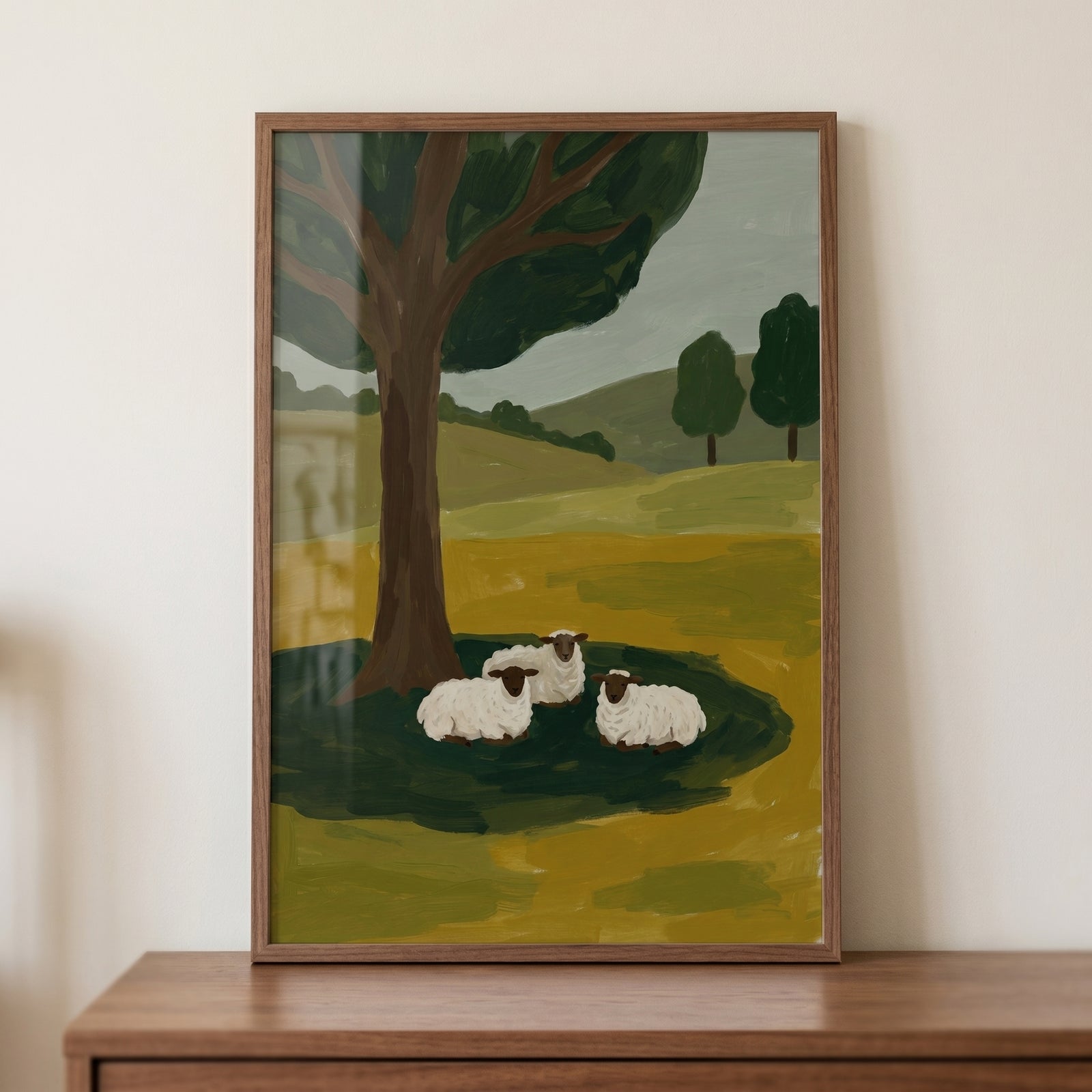 Three sitting woolly sheep wall art depicts a pastoral scene with a large tree and rolling green hills.