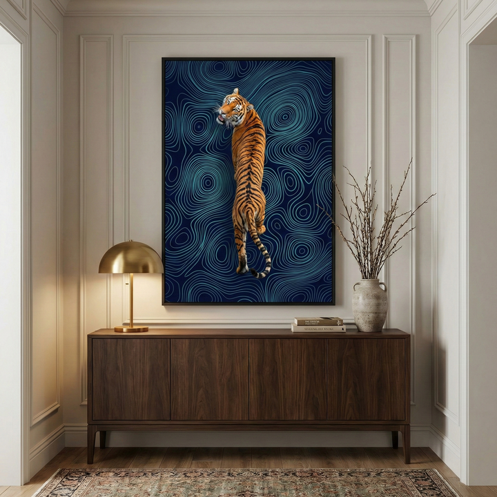 An elegant interior scene showcases a large, vertical piece of wall art centered above a dark wood sideboard. The artwork depicts a tiger from a rear view, its body twisting as it looks back over its shoulder. The tiger’s bright orange fur and black stripes stand out against a dark blue background filled with an intricate pattern of light blue, wavy lines that resemble a topographical map.