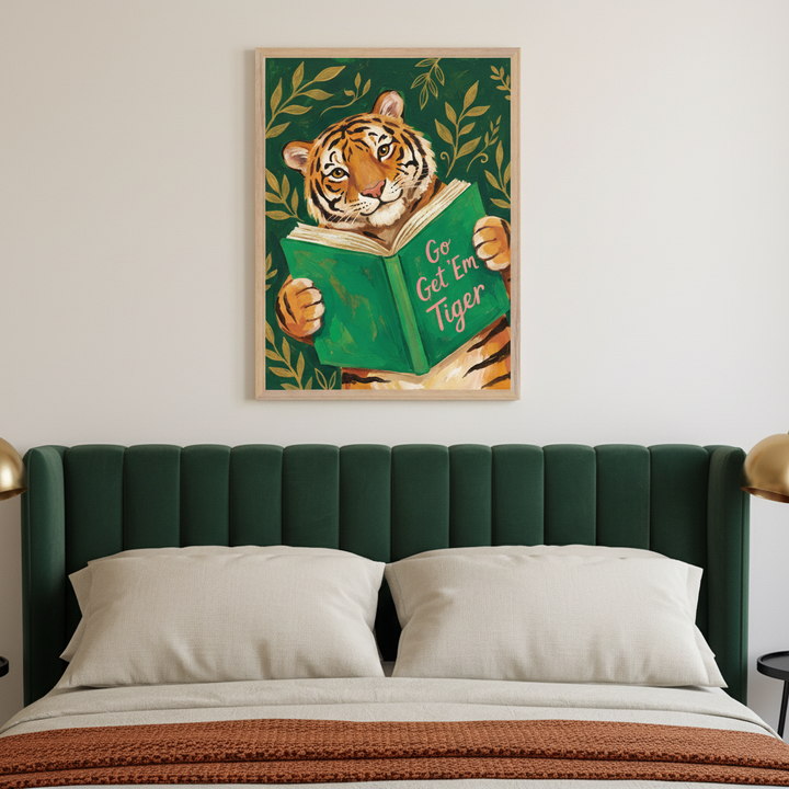 Modern bedroom with a dark green upholstered bed. A framed painting of a tiger reading a green book titled "Go Get Em Tiger" with golden leaves on a dark green background hangs centered above the bed.