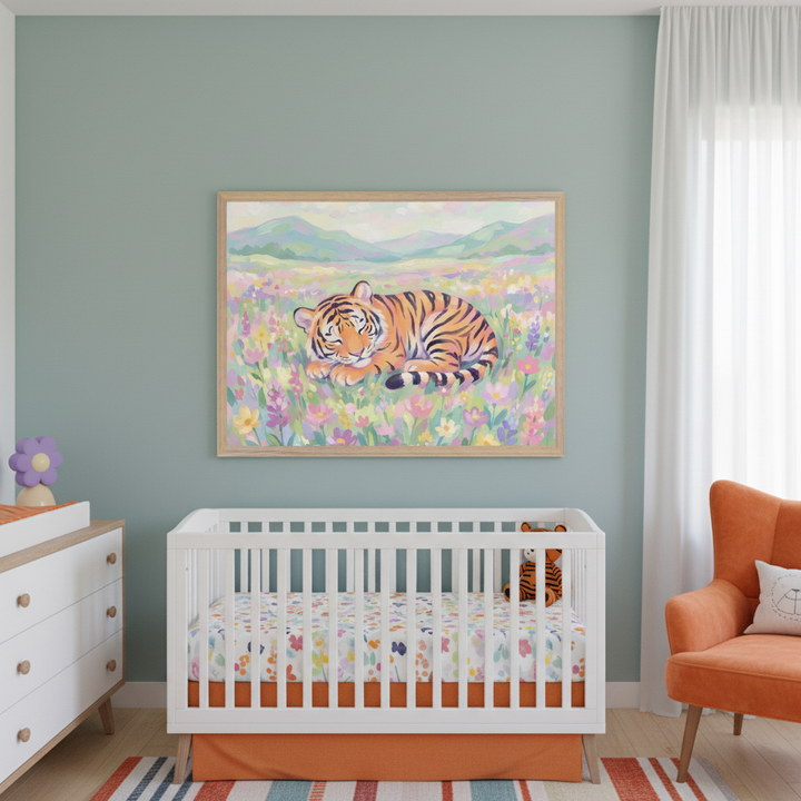 Modern nursery with sage green walls. A large framed print of a sleeping tiger in a colorful flower field hangs centered above a white crib with an orange bed skirt. A white dresser is left, an orange armchair right.