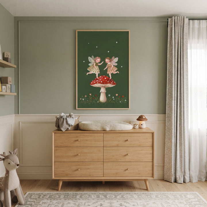 Wooden dresser in a nursery with framed toadstool dancing garden fairies wall art on a sage green wall.