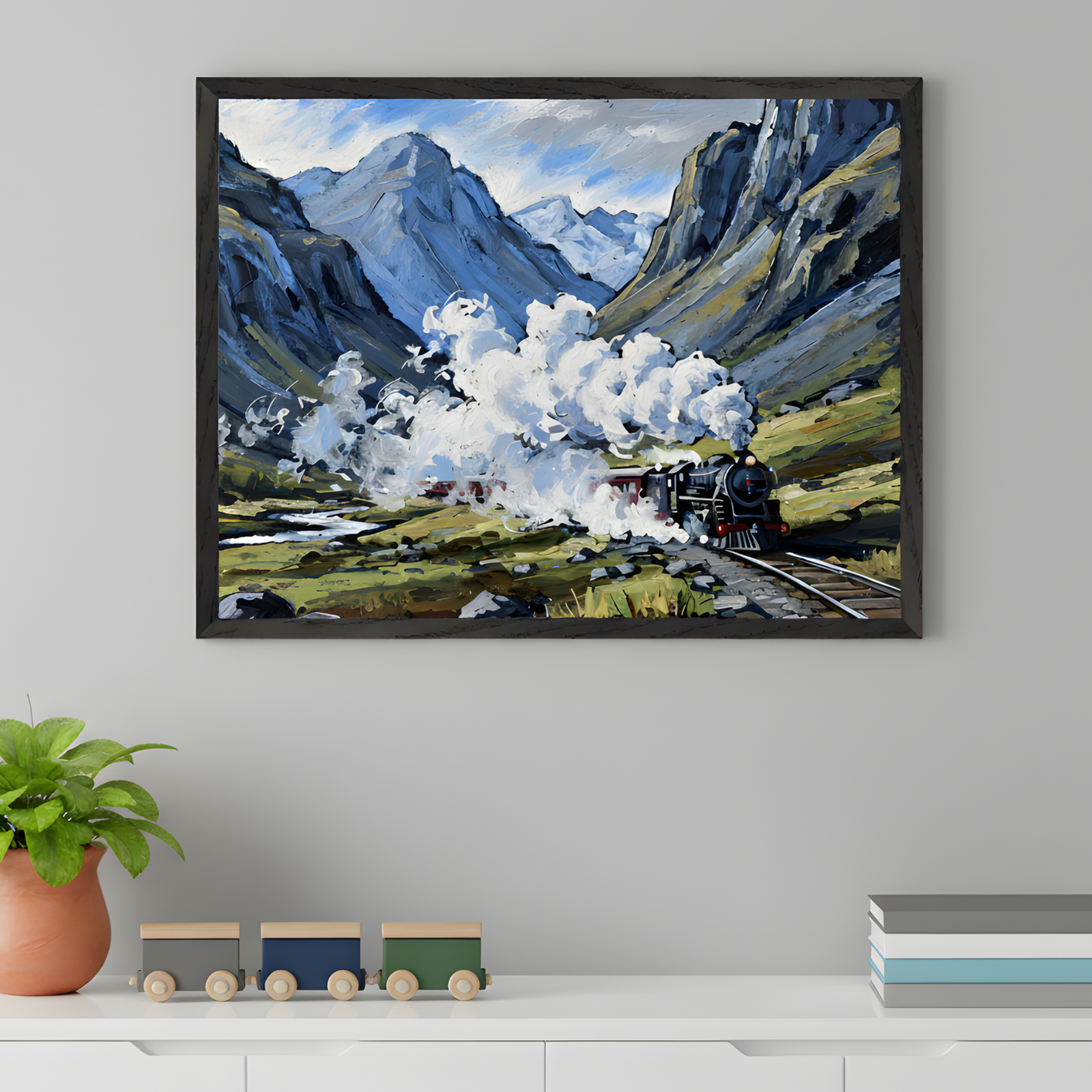 A framed artwork of a steam train chugging through a dramatic mountain valley, with thick white smoke billowing into a blue sky. The artwork hangs above a white dresser decorated with a potted plant, a wooden toy train, and a stack of books.