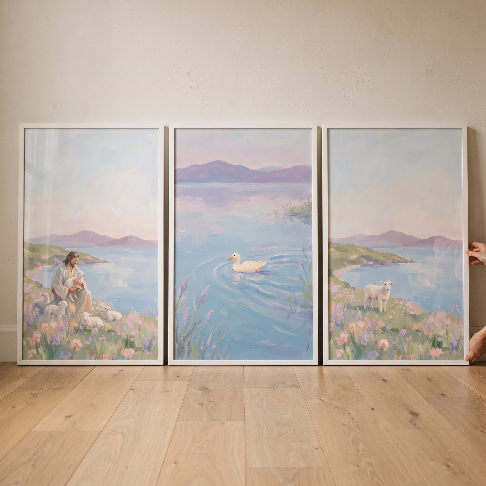 Jesus with sheep, a duck, and a lamb in a tranquil lilac mountain coastal wall art set of 3 on a light wood floor.