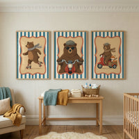A set of three framed vertical illustrations hangs on a light-colored wall with a subtle, textured pattern. The artwork features a whimsical theme of animals on the move, each set within an ornate, scroll-edged border against a background of blue and cream vertical stripes.

The illustration on the left shows a brown bear happily roller-skating, its body leaning forward and a long, light blue scarf trailing behind it.

