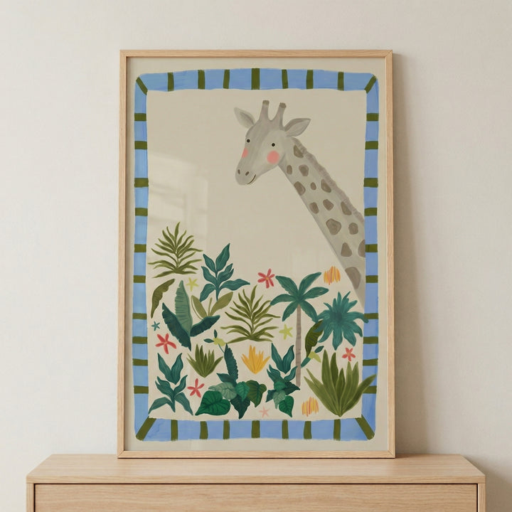 Framed illustration of a tall giraffe with a gentle expression peeking above a cluster of green tropical plants and small colorful flowers. The soft cream background and blue striped border create a playful and calming jungle themed print.