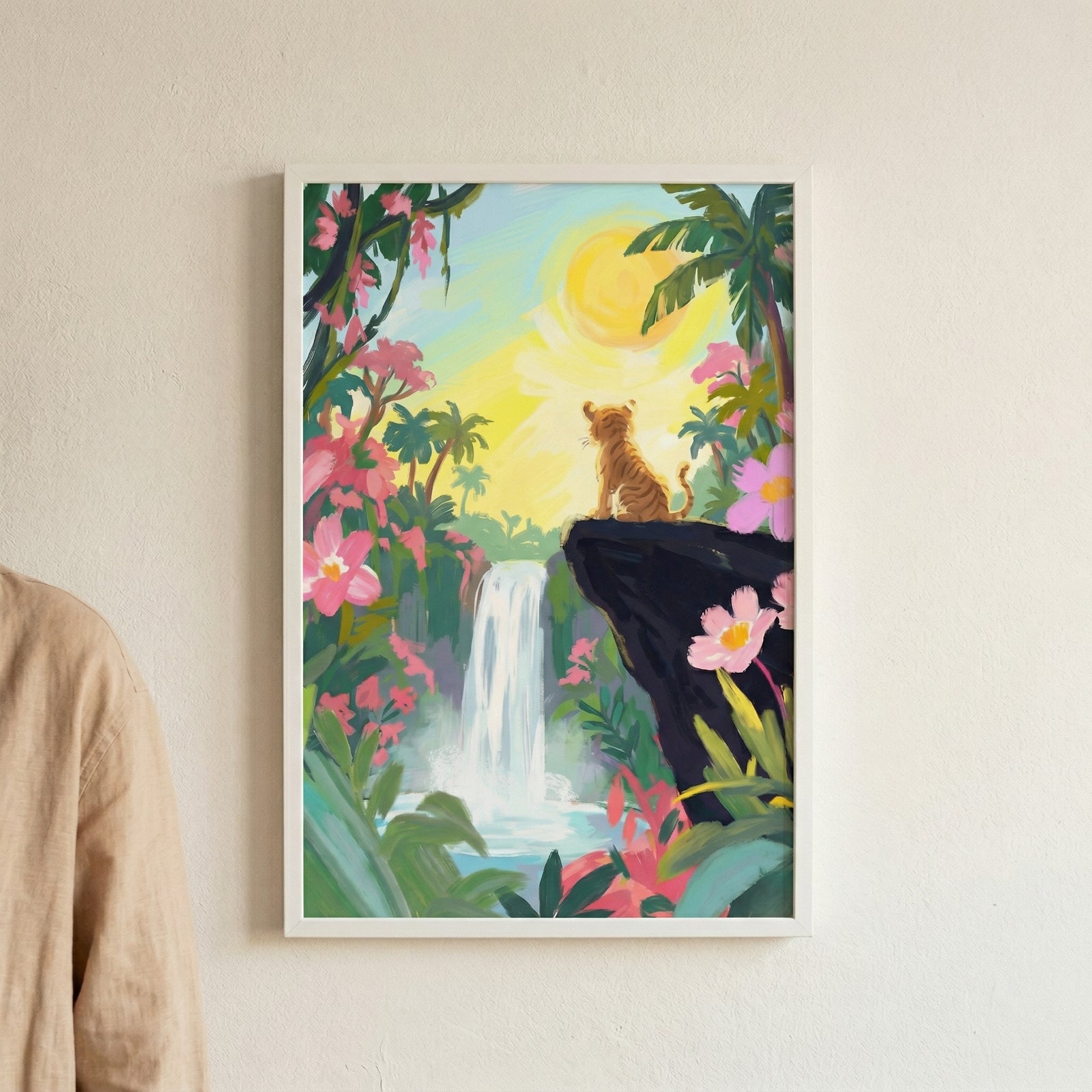 An art print of a small tiger cub sitting on the edge of a dark rock cliff, looking out over a lush tropical landscape. A cascading waterfall is centered in the distance, surrounded by dense green jungle foliage, palm trees, and vibrant pink flowers. A large, bright yellow sun shines in the pale sky, creating a warm, golden glow across the entire scene.