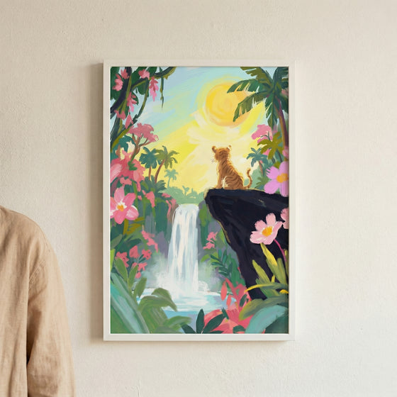 An art print of a small tiger cub sitting on the edge of a dark rock cliff, looking out over a lush tropical landscape. A cascading waterfall is centered in the distance, surrounded by dense green jungle foliage, palm trees, and vibrant pink flowers. A large, bright yellow sun shines in the pale sky, creating a warm, golden glow across the entire scene.