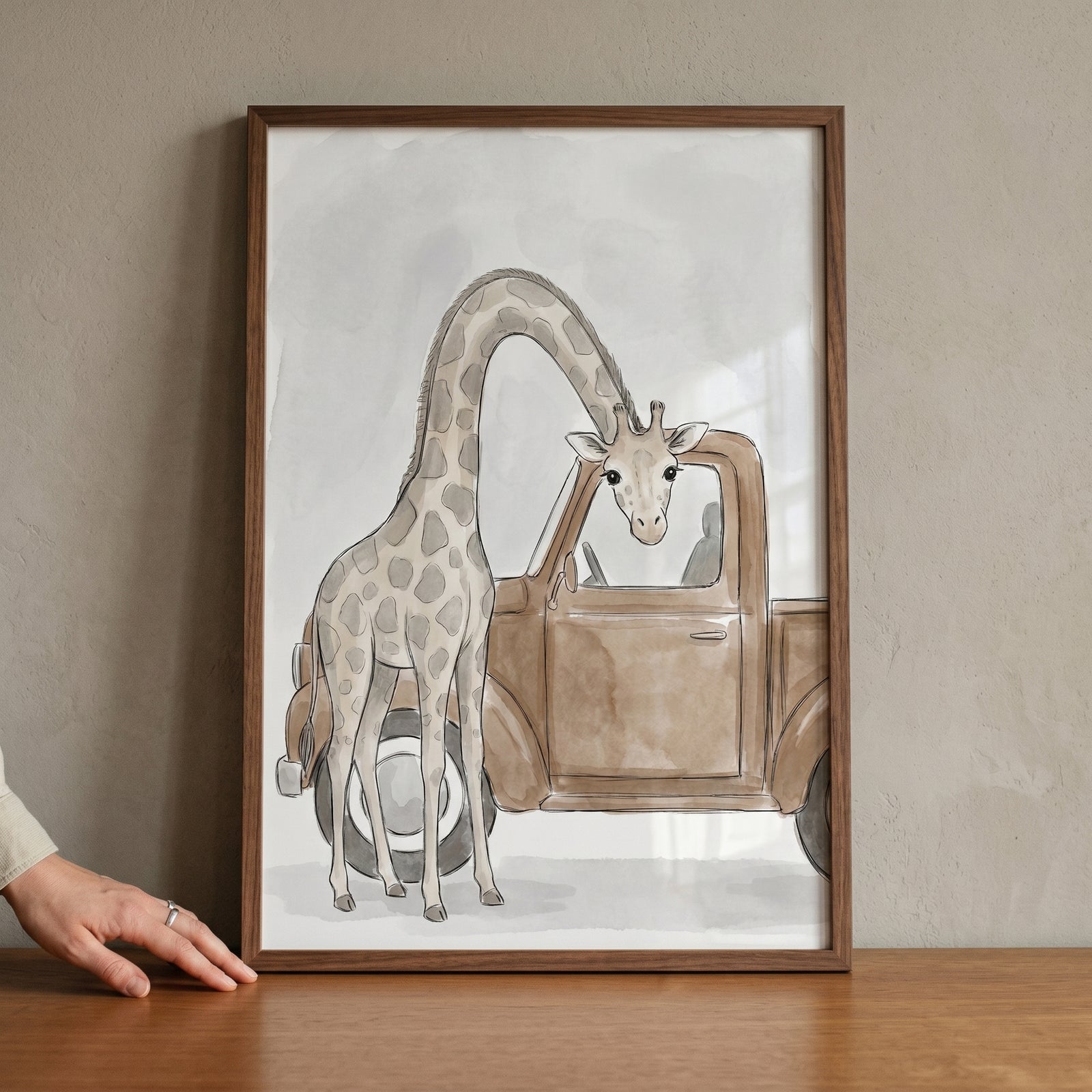 Watercolor illustration of truck window peeking giraffe wall art framed in wood on a neutral wall.