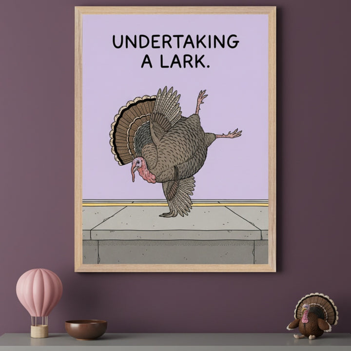 Modern room with a plum wall. A framed illustration of a turkey in a ballet pose on a sidewalk, with "UNDERTAKING A LARK" text, hangs above a gray shelf. A pink hot air balloon, brown bowl, and turkey toy are on the shelf.