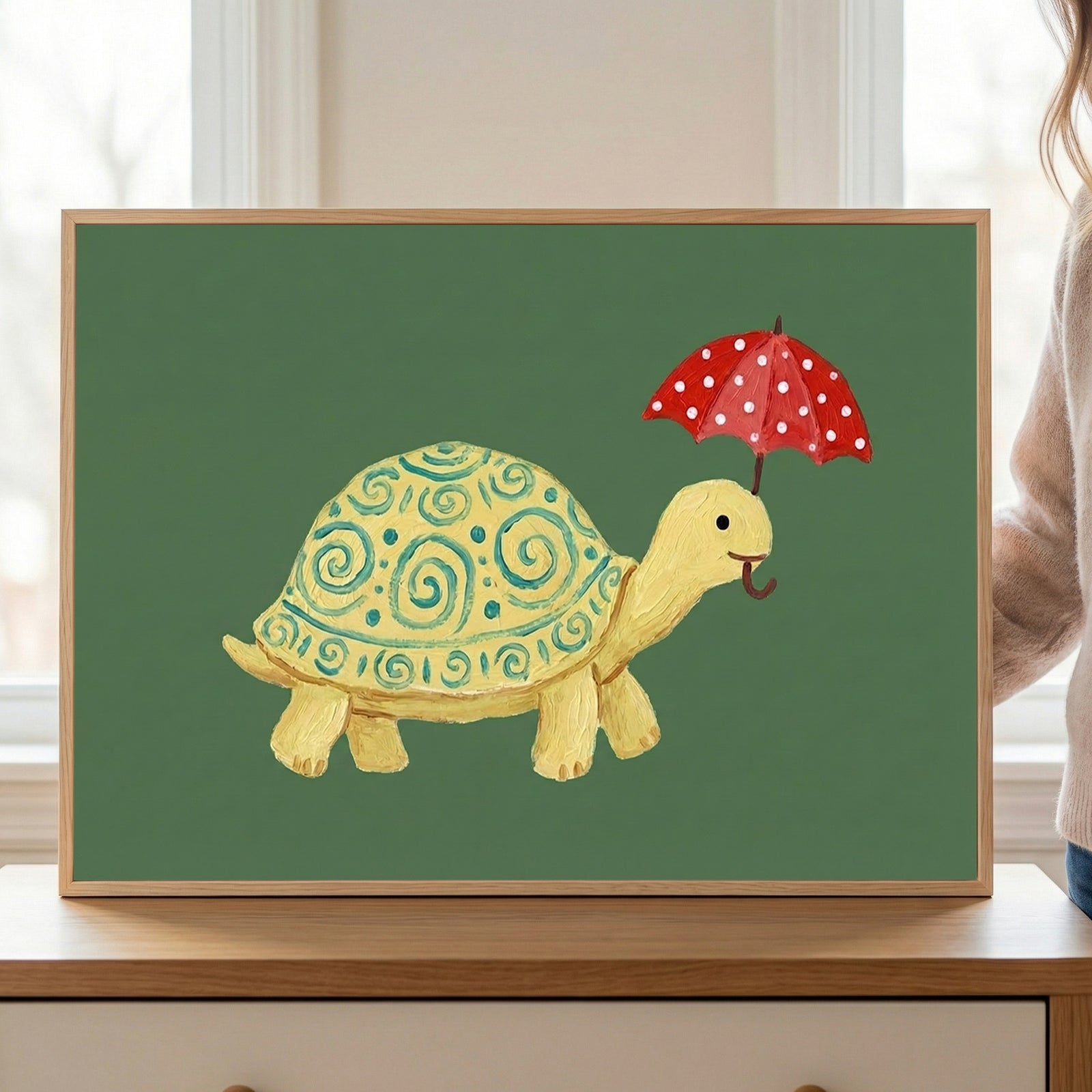 A whimsical painting of a yellow turtle with teal spiral patterns on its shell, holding a red polka-dot umbrella with its mouth. The turtle stands out playfully against a muted green background.