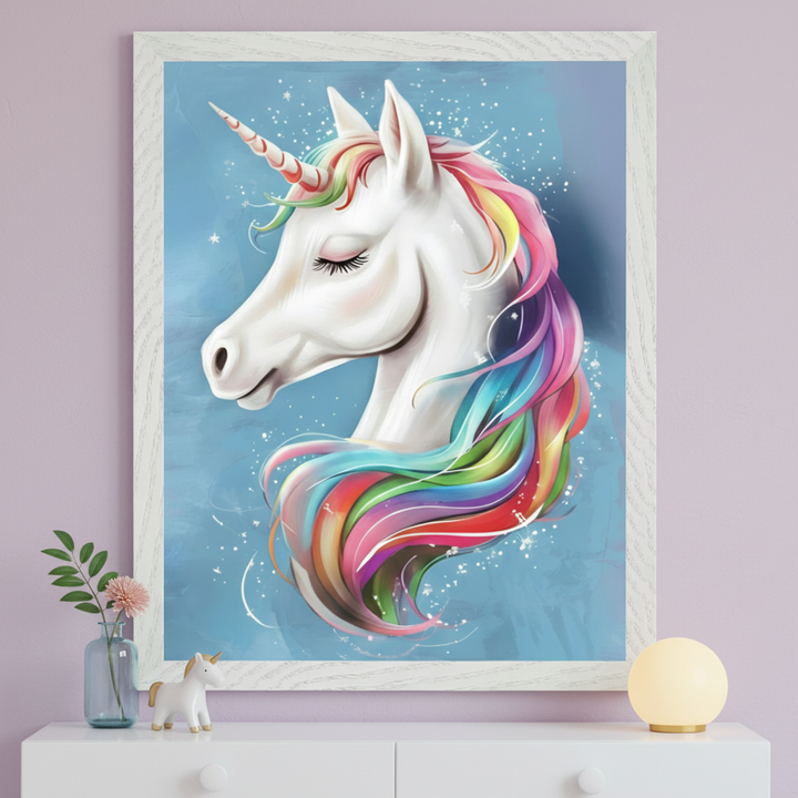 Kid's bedroom with a white dresser. A large framed illustration of a white unicorn head with a rainbow mane and closed eyes, on a blue background, hangs centered above the dresser. A small unicorn figurine, a vase with a flower, and a spherical lamp are on the dresser.