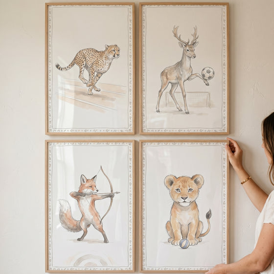 Vine border sports animals wall art set of 4 shows a running cheetah, soccer deer, archery fox, and sitting lion cub.