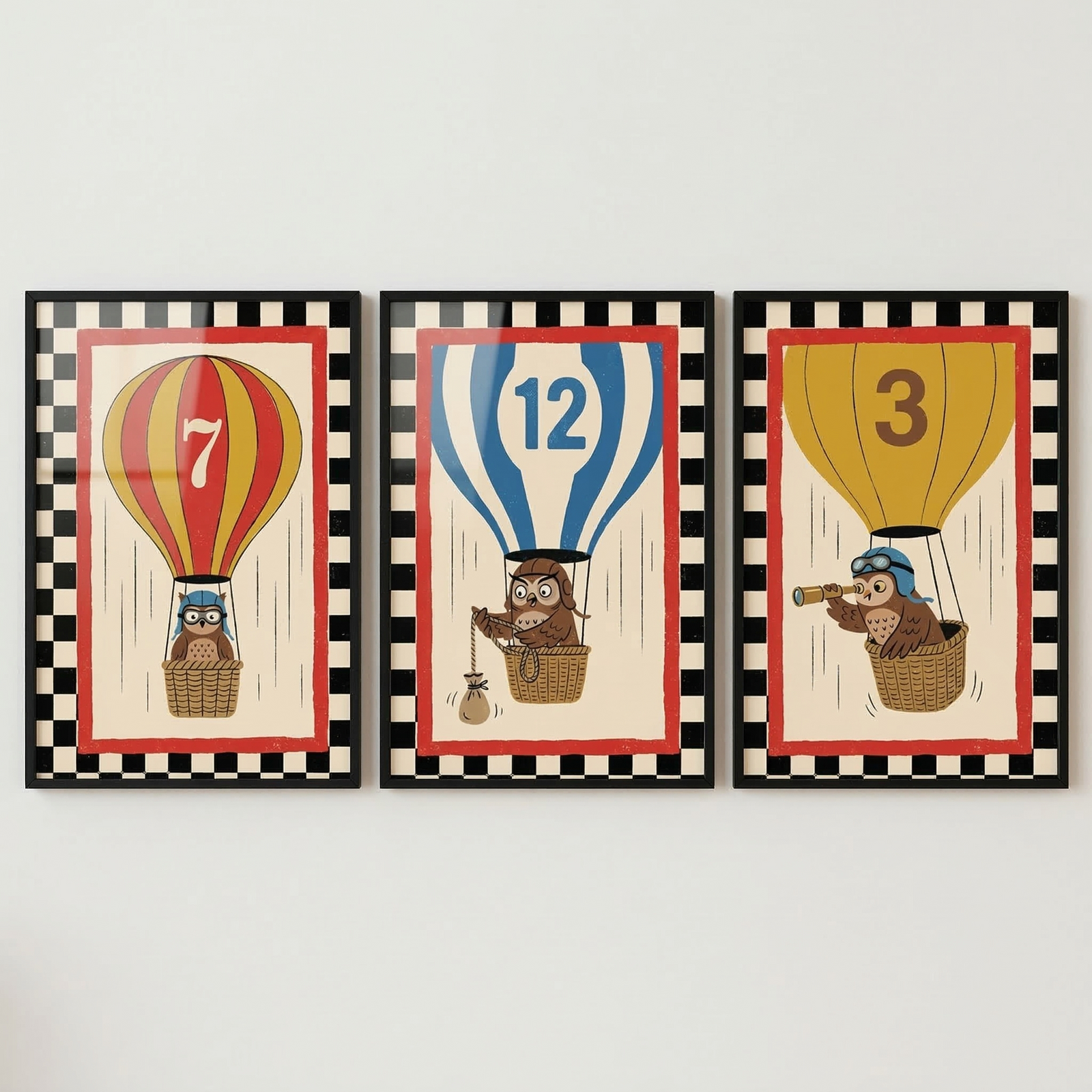 A set of three framed vertical illustrations featuring cute cartoon owls in hot air balloons. Each piece is bordered by a black-and-white checkered pattern and a red inner frame. The first piece shows an owl in a basket beneath a red and yellow striped balloon with a large number "7". The second features an owl wearing a pilot's cap in a basket under a blue and white striped balloon with the number "12". The third depicts an owl using a telescope under a yellow balloon with the number "3".