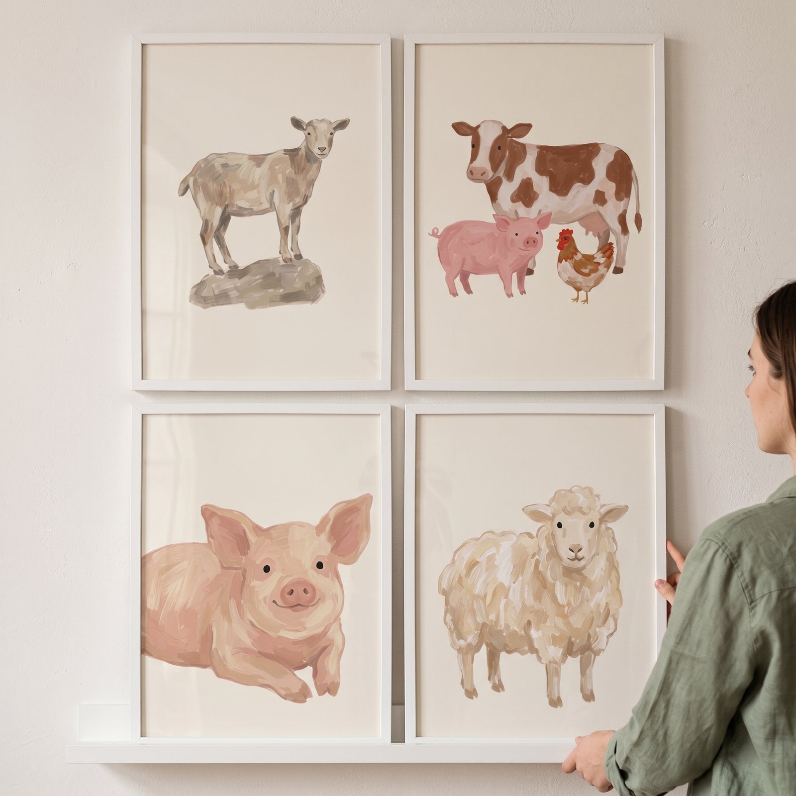 Woman placing vintage beige farm animals wall art set of 4 featuring a goat, cow, pig, chicken, and sheep on a wall.