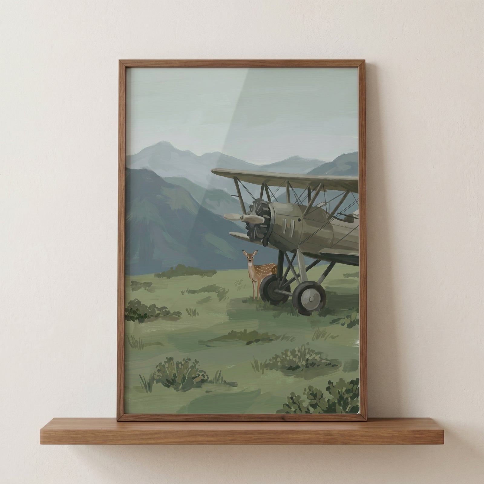 Framed vintage biplane mountain fawn wall art shows a deer by a classic aircraft in a grassy field below mountains.