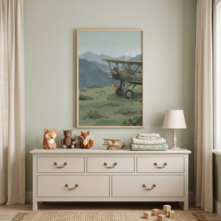 Dresser with animal figurines and a lamp under vintage biplane mountain fawn wall art in a sage green nursery.