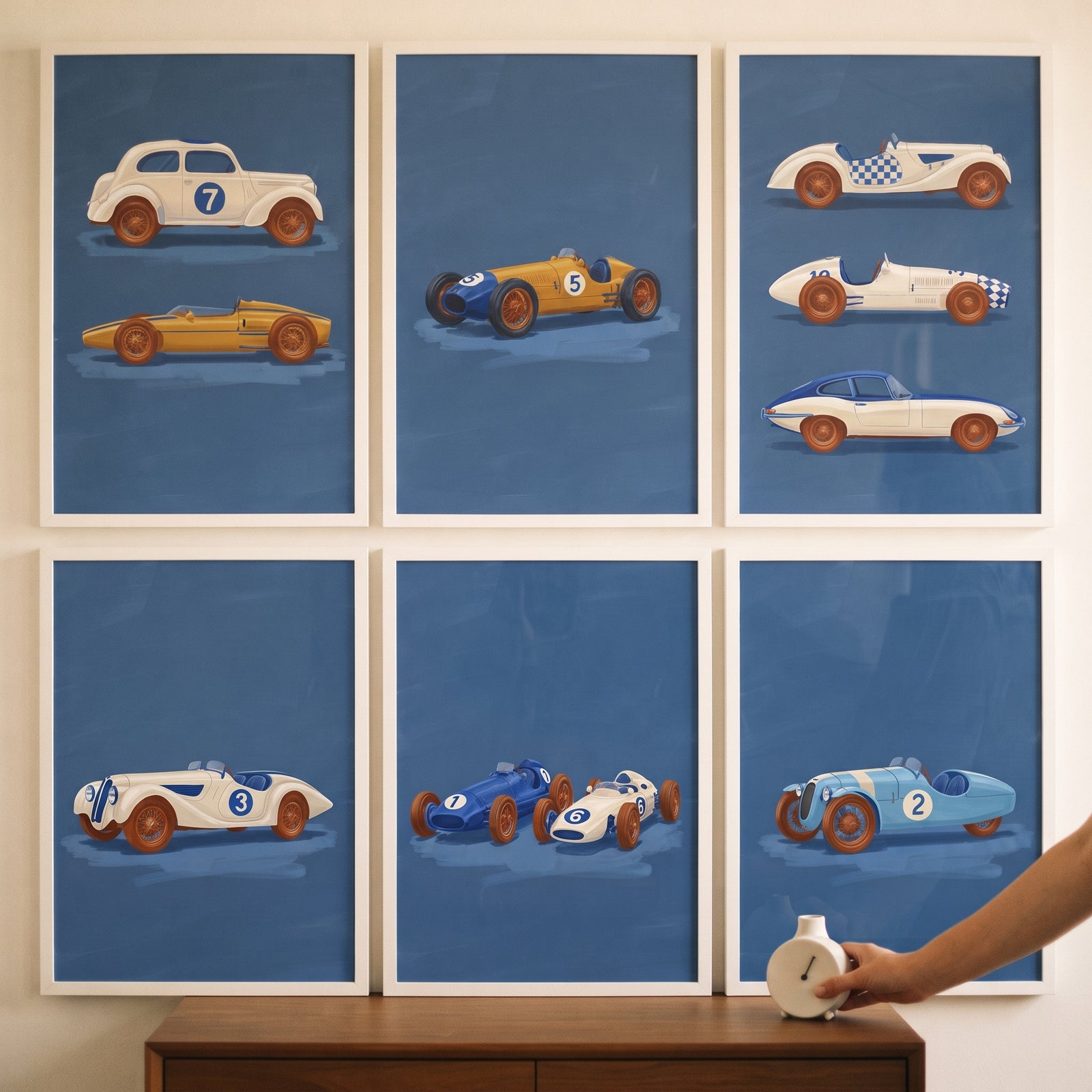 Vintage blue racing car wall art set of 6 hanging in white frames on a wall above a wooden cabinet.
