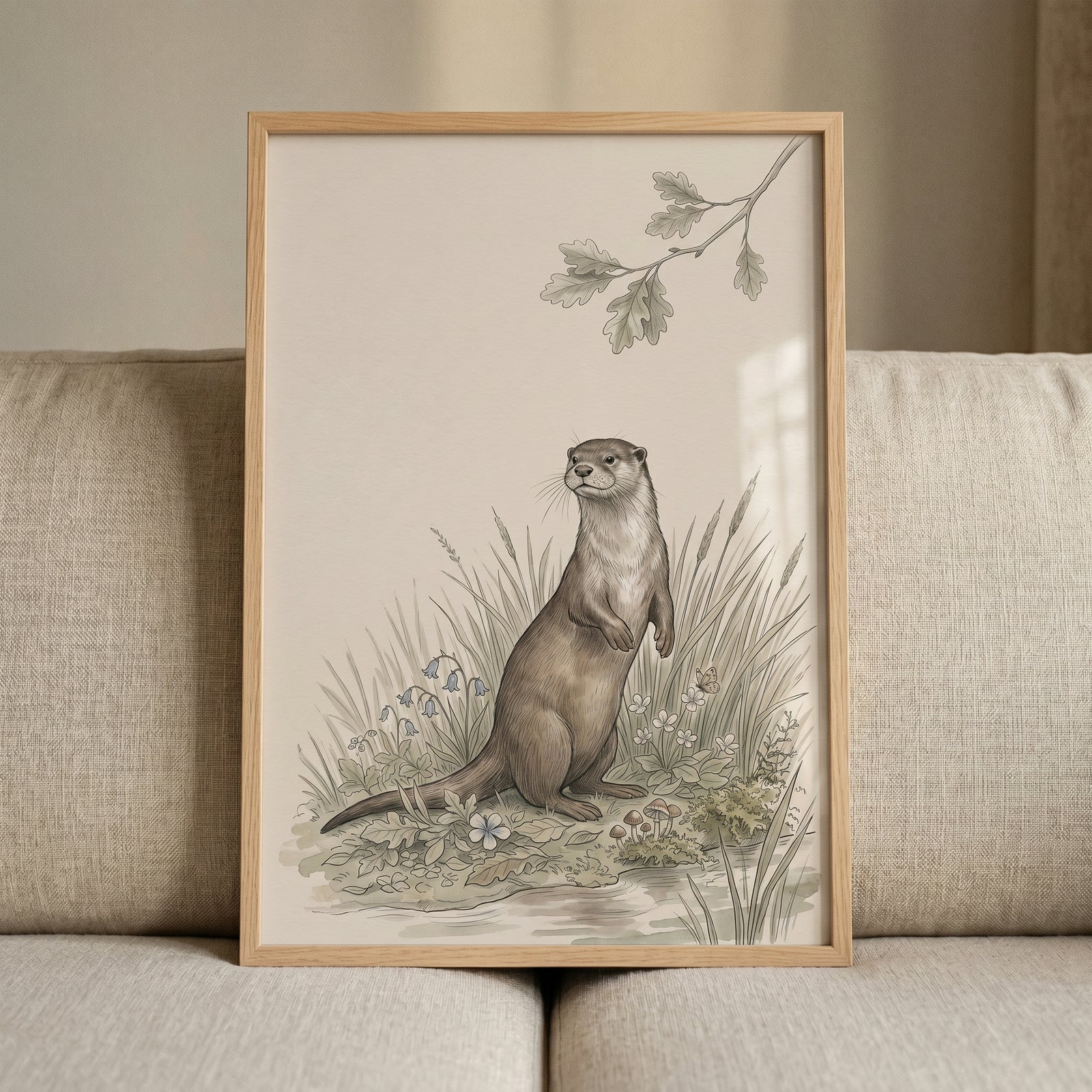 Vintage botanical otter wall art in a wood frame on a sofa shows a standing otter near wildflowers under an oak branch.