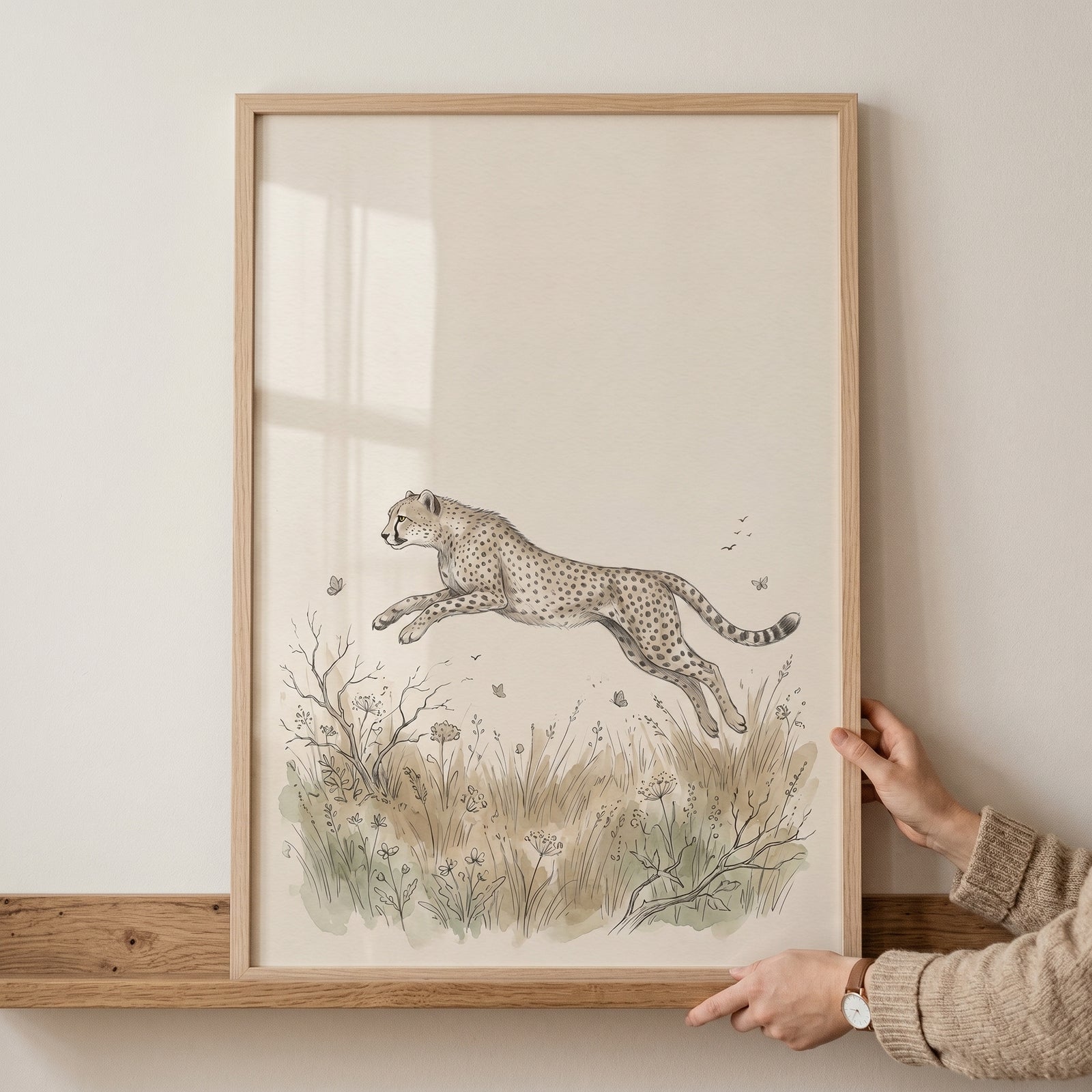 Vintage earth tone cheetah artwork featuring a leaping cheetah over a grassy field, held in a light wood frame.