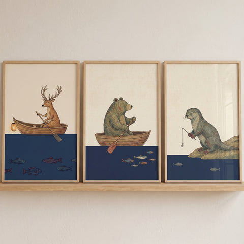 Vintage fishing woodland animals wall art set of 3 with a deer in a boat, bear rowing, and otter fishing on blue water.