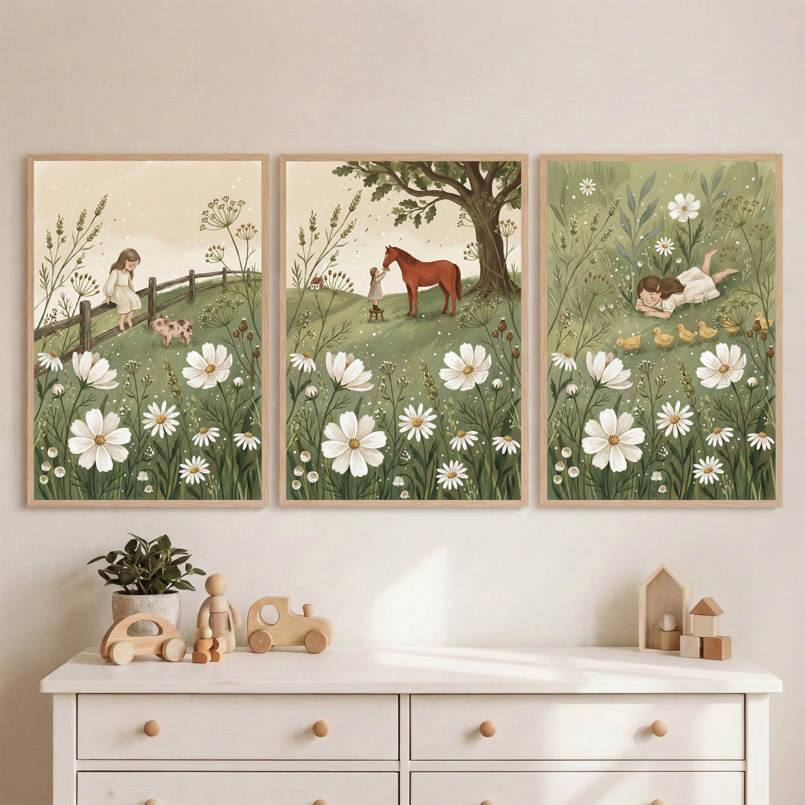 Three framed meadow illustrations hang above a white dresser with wooden toys and a small plant. The scenes show a child walking beside a fence with a piglet standing under a large tree with a horse and lying in the grass watching ducklings among tall daisies and wildflowers.