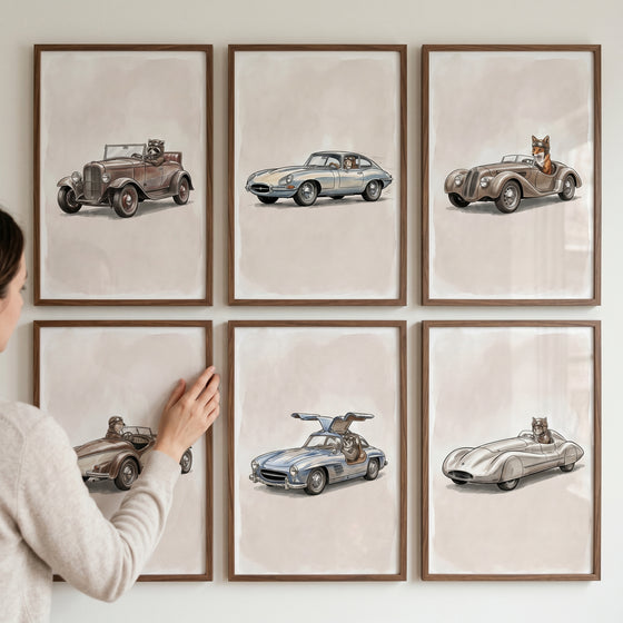 Hand adjusts a vintage goggles racing animal wall art set of 6 featuring animals in classic cars on a neutral wall.