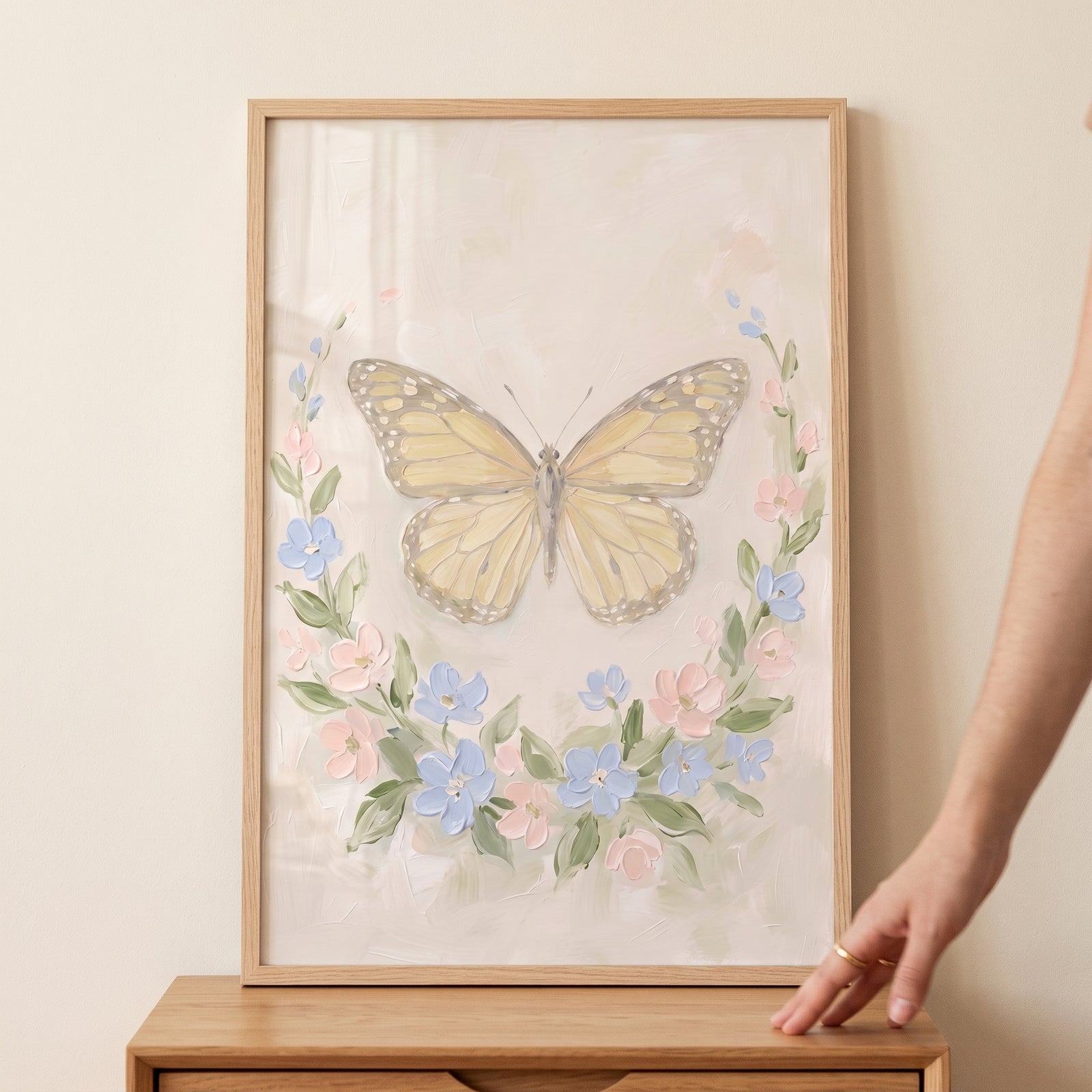 Vintage pastel floral butterfly wall art in a wood frame features a soft butterfly and a wreath of pink and blue flowers.