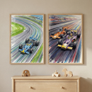 Two framed illustrations of open-wheel race cars hang on a neutral wall above a wooden dresser. The left art shows a blue car numbered 20 on a curved track near the coast. The right art depicts an orange car and a purple-and-yellow car racing side-by-side with vibrant motion lines behind them. Both pieces feature a dynamic, sketch-like style with colorful washes. On the dresser sit three simple wooden toys: a car, a stacking toy, and a small horse silhouette.