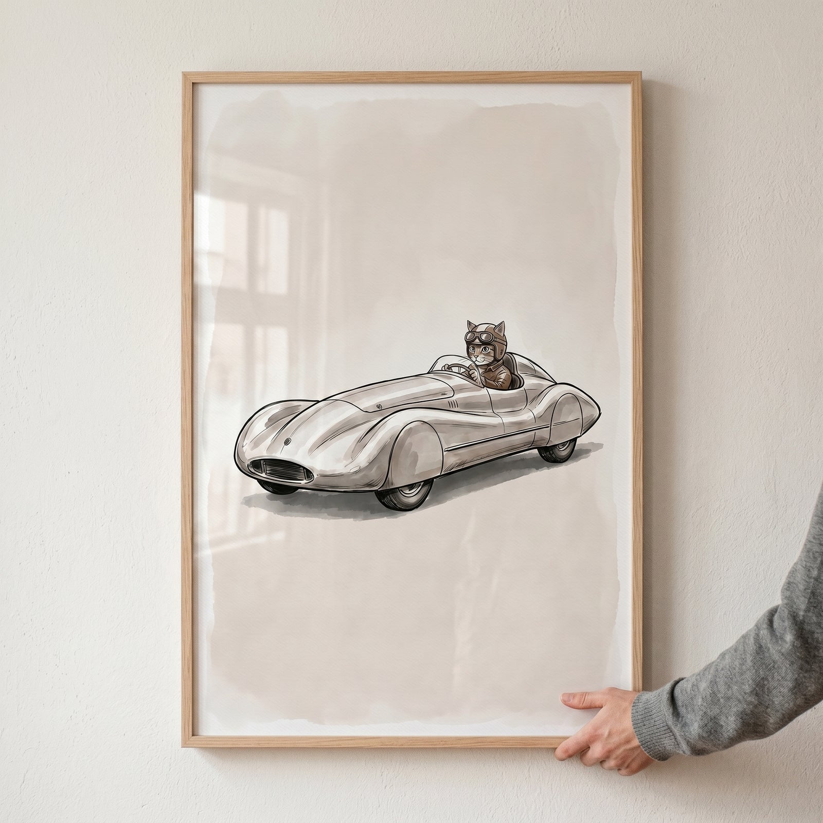 Vintage racing driving cat wall art features a cat in goggles and a helmet steering a sleek, silver classic race car.