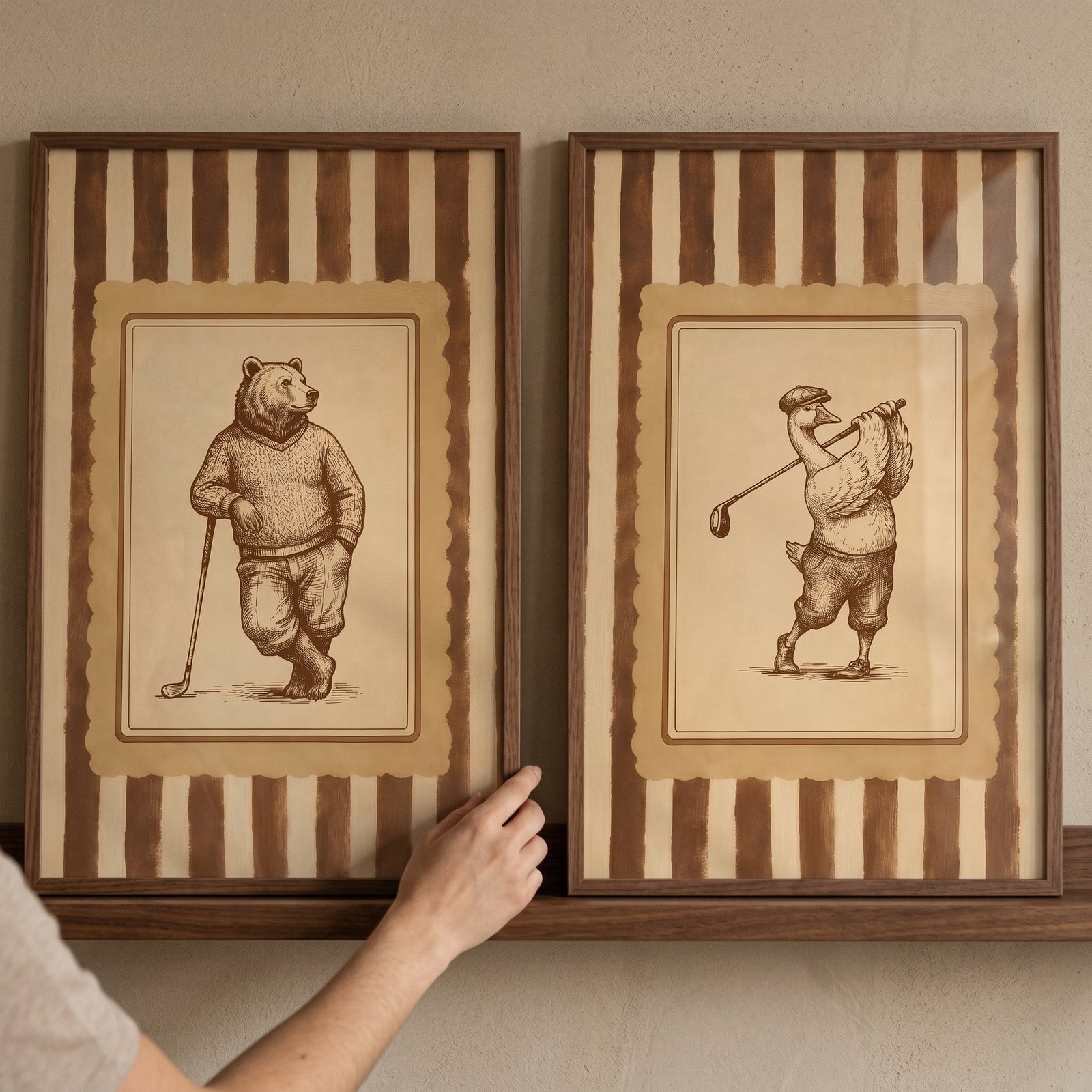 Hand holds vintage sepia golfing animal wall art set of 2 featuring a bear and a goose in classic golf attire.