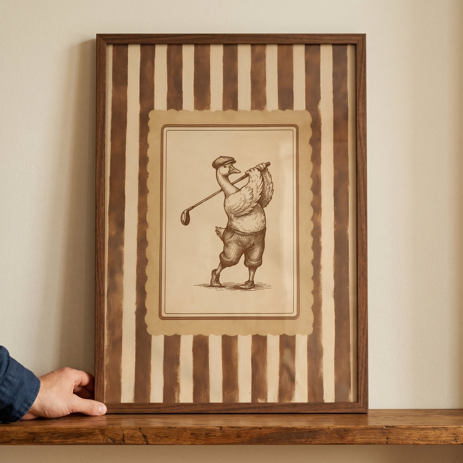 Framed vintage sepia golfing goose wall art of a goose in a cap and knickers, displayed on a wooden shelf.