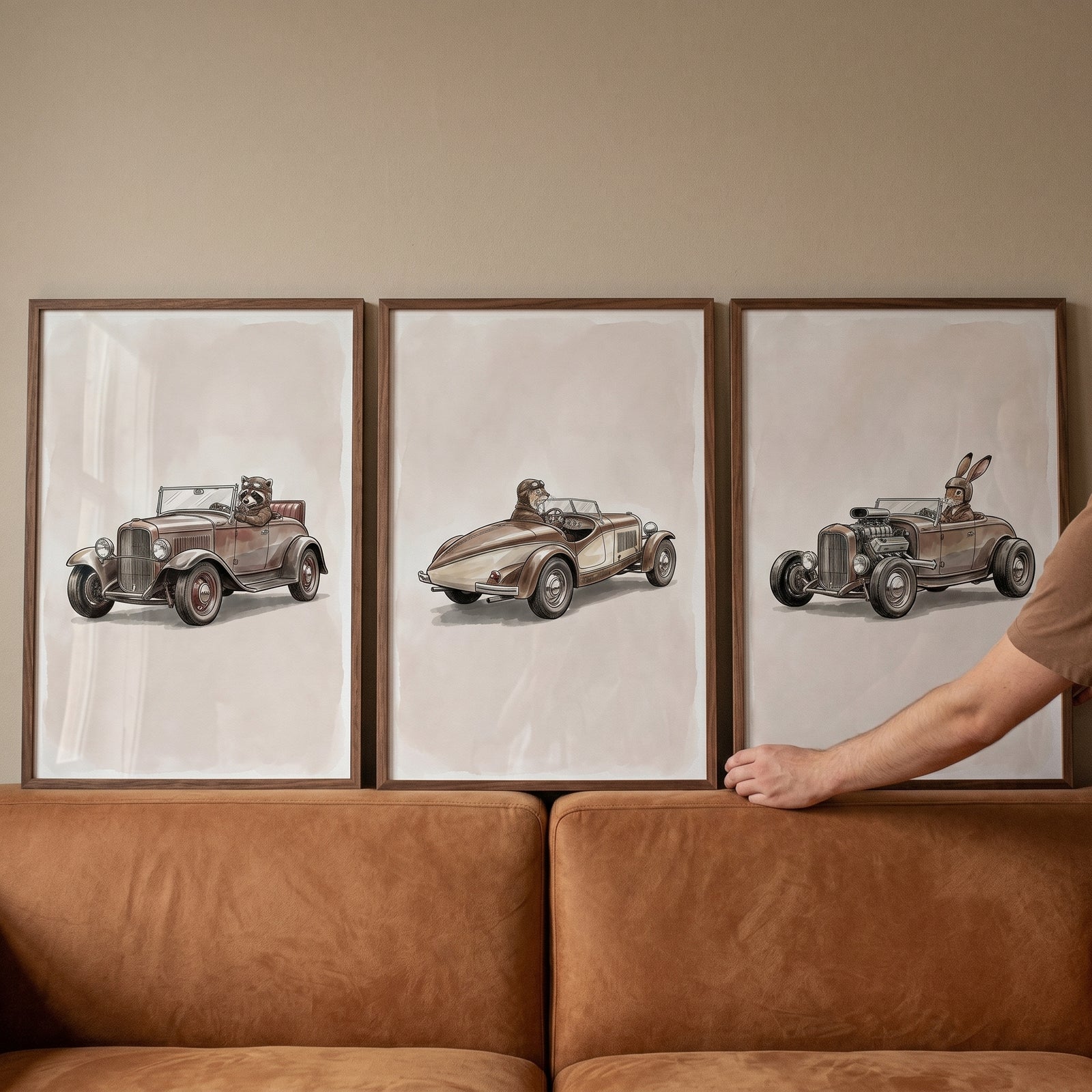 Vintage speedster driving animal wall art set of 3 displayed above a tan sofa with a hand touching the frame.
