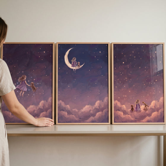 A woman adjusts a violet night girl dog wall art set of 3 on a shelf, showing a girl and dog among stars and clouds.