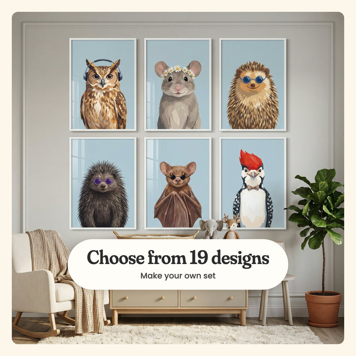 Nursery with six animal portrait prints in white frames in two rows on a panelled wall, above a light wood dresser with a woven tray, a plush elephant and a plush deer, beside a cream rocking chair with a knit throw and a fiddle-leaf fig on a shaggy rug: an owl in black headphones, a mouse in a daisy crown, a hedgehog in blue round shades, a porcupine in purple round glasses, a bat in round dark sunglasses and a woodpecker in a polka-dot bow tie, labeled Choose from 19 designs, Make your own set