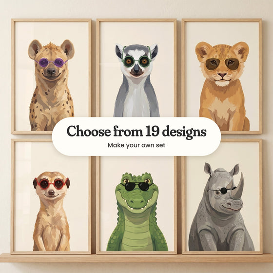 Six dapper safari animal prints in light wood frames in two rows on a wood ledge against a cream wall: a hyena in purple sunglasses, a lemur in green glasses, a lion cub in gold aviators, a meerkat in red glasses, a crocodile in black sunglasses and a rhino in black sunglasses, with a label reading Choose from 19 designs, Make your own set