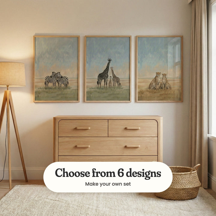 Cream nursery with three animal family prints in light wood frames above a rounded light wood dresser, beside a tripod floor lamp and a woven basket: Striped Wild Unity, Gentle Savanna Trio and Savanna Family Trio, with a label reading Choose from 6 designs, Make your own set
