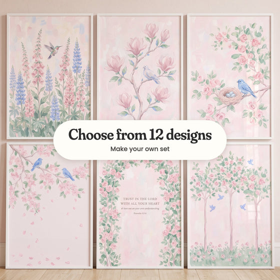 Six blush pink garden prints in white frames in two rows against a pale pink wall: a hummingbird among pink foxgloves and blue lupines, a dove on a magnolia branch, a bluebird by a nest of blue eggs, two bluebirds on a blossom branch, a rose arch with the verse Trust in the Lord with all your heart and three rose trees with bluebirds, with a label reading Choose from 12 designs, Make your own set