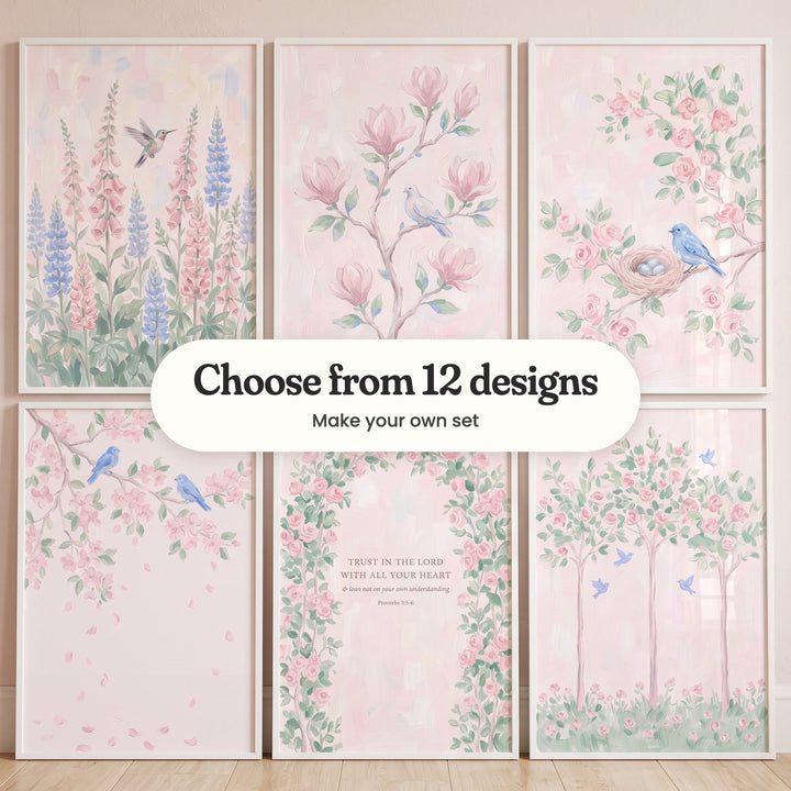 Six blush pink garden prints in white frames in two rows against a pale pink wall: a hummingbird among pink foxgloves and blue lupines, a dove on a magnolia branch, a bluebird by a nest of blue eggs, two bluebirds on a blossom branch, a rose arch with the verse Trust in the Lord with all your heart and three rose trees with bluebirds, with a label reading Choose from 12 designs, Make your own set