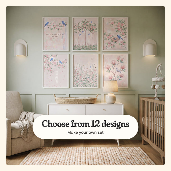Nursery with six blush pink garden prints in white frames between two white sconces on a sage green wall, above a white dresser with a woven changing basket and a lamp, beside an armchair and a wood crib with a mobile: two bluebirds with a Bible verse, three rose trees, a bluebird by a nest, two bluebirds on a blossom branch, bees over wildflowers and a dove on magnolia, labeled Choose from 12 designs, Make your own set