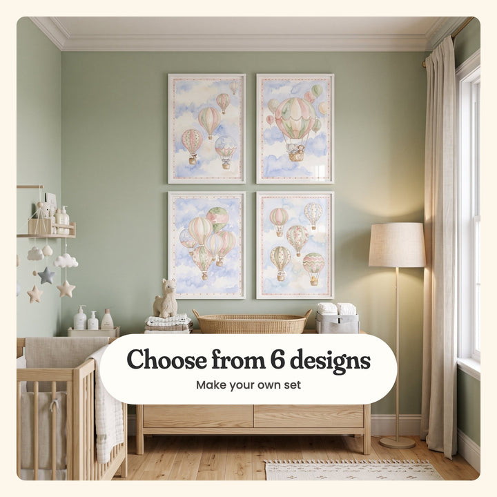 Nursery with four hot air balloon prints in white frames in two rows on a sage green wall above a wood changing dresser with a woven basket and a plush llama, beside a wood crib, a cloud and star mobile and cream curtains: balloons with a fawn and a koala, a big balloon with an elephant and a monkey, a cluster with a teddy bear and a fawn, and balloons with a bunny, a lamb and a duckling, labeled Choose from 6 designs, Make your own set