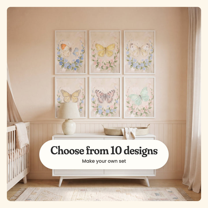 Nursery with six butterfly prints in white frames in two rows on a blush wall over beadboard, above a white dresser with a ceramic lamp and a woven basket, beside a white crib with a canopy: an orange-tip and a blue butterfly, a buttery yellow butterfly, a cream white butterfly, a soft yellow butterfly, a blush and grey butterfly and a mint green butterfly, each in a flower wreath, labeled Choose from 10 designs, Make your own set