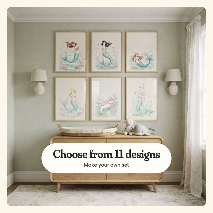 Nursery with six mermaid prints in light wood frames in two rows between two ceramic wall lamps on a sage green wall, above a wood sideboard with a woven changing basket, a plush lamb and a plush whale: a brown-haired mermaid swimming, a dark-haired mermaid among cattails, a mermaid in water lilies, a blonde mermaid, a pink-haired mermaid on lily pads and a mermaid reaching for butterflies, labeled Choose from 11 designs, Make your own set
